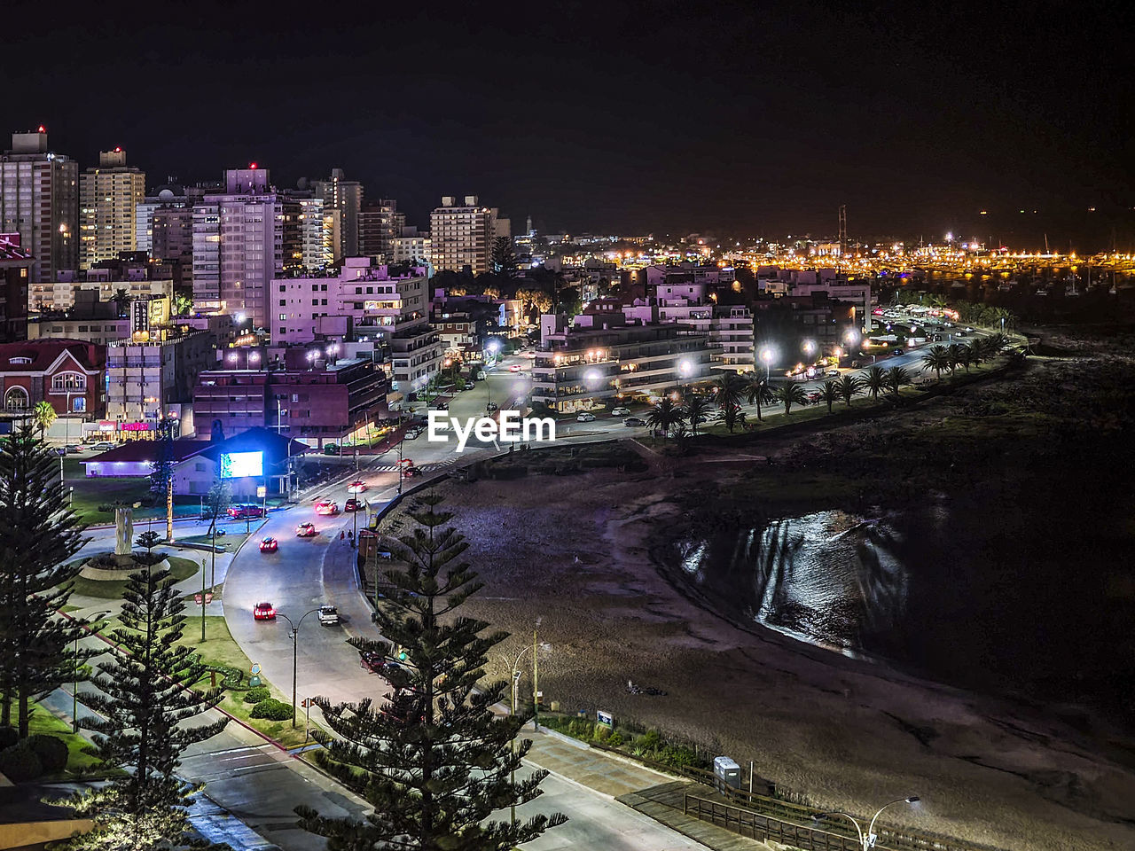 HIGH ANGLE VIEW OF ILLUMINATED STREET AMIDST BUILDINGS IN CITY AT NIGHT