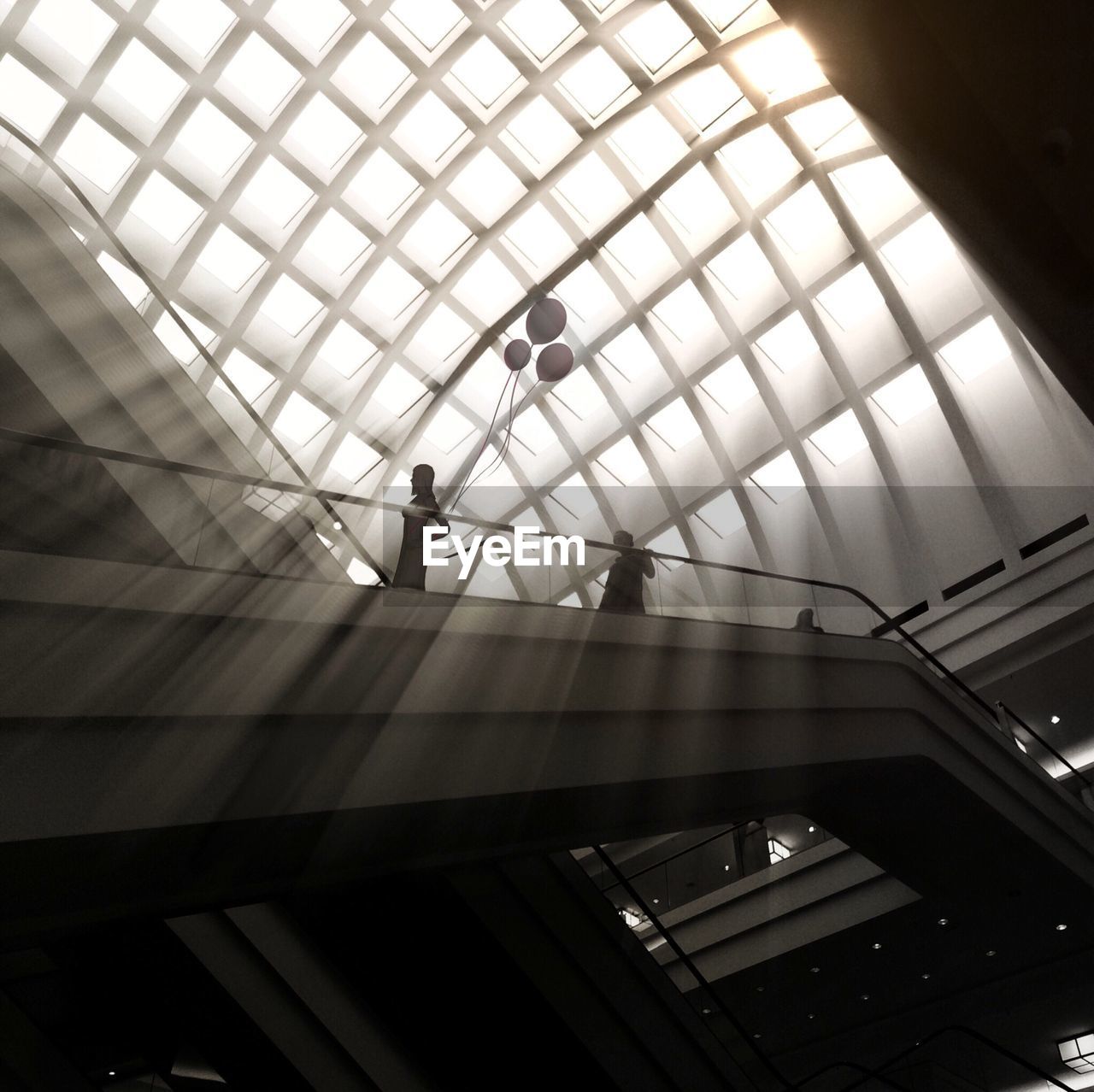 Low angle view of people on escalator in shopping mall