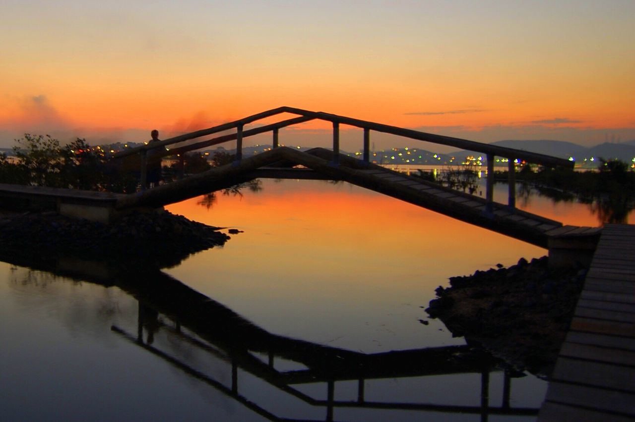 BRIDGE OVER CALM RIVER AT SUNSET