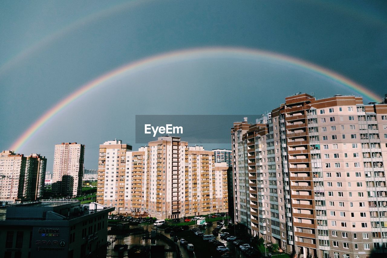 Rainbow over city against sky