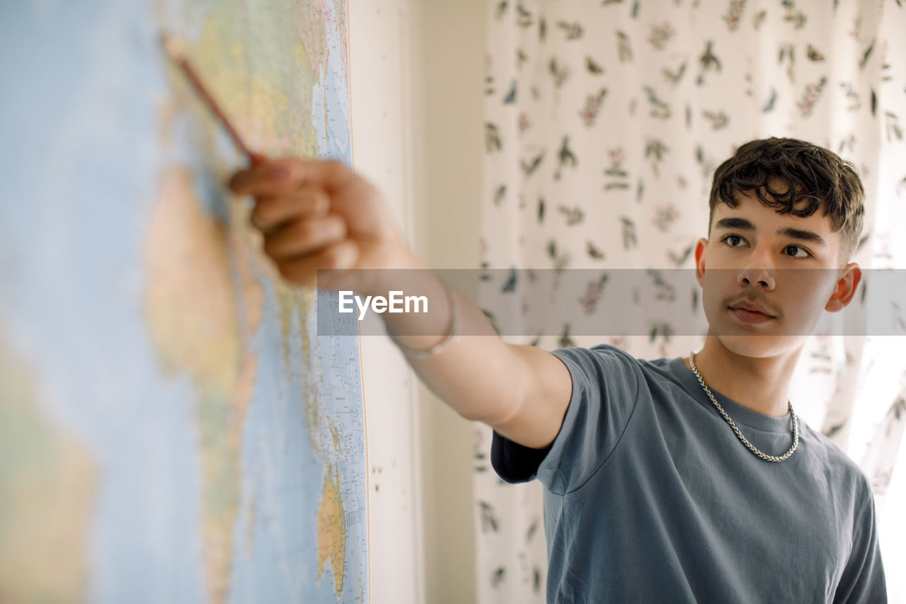 Teenage boy explaining over world map in classroom