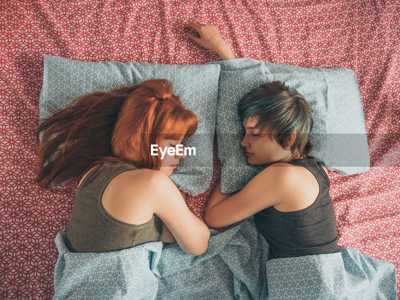 Lesbian couple sleeping on bed at home