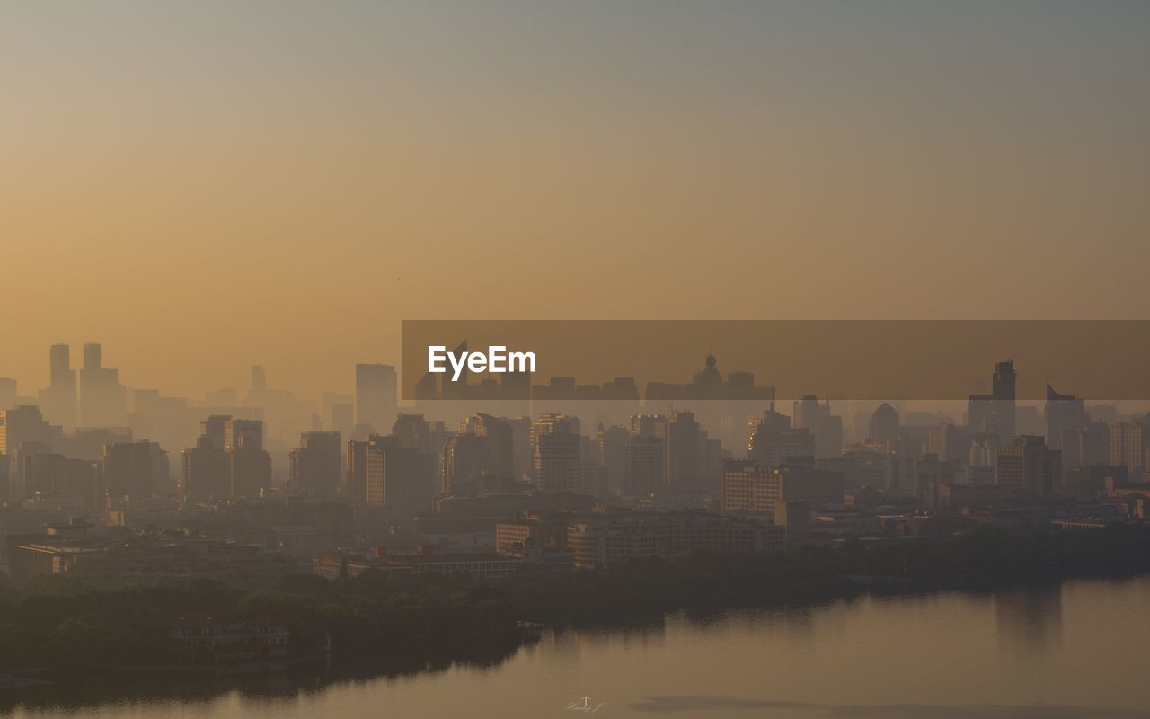 Buildings in city against clear sky during sunset