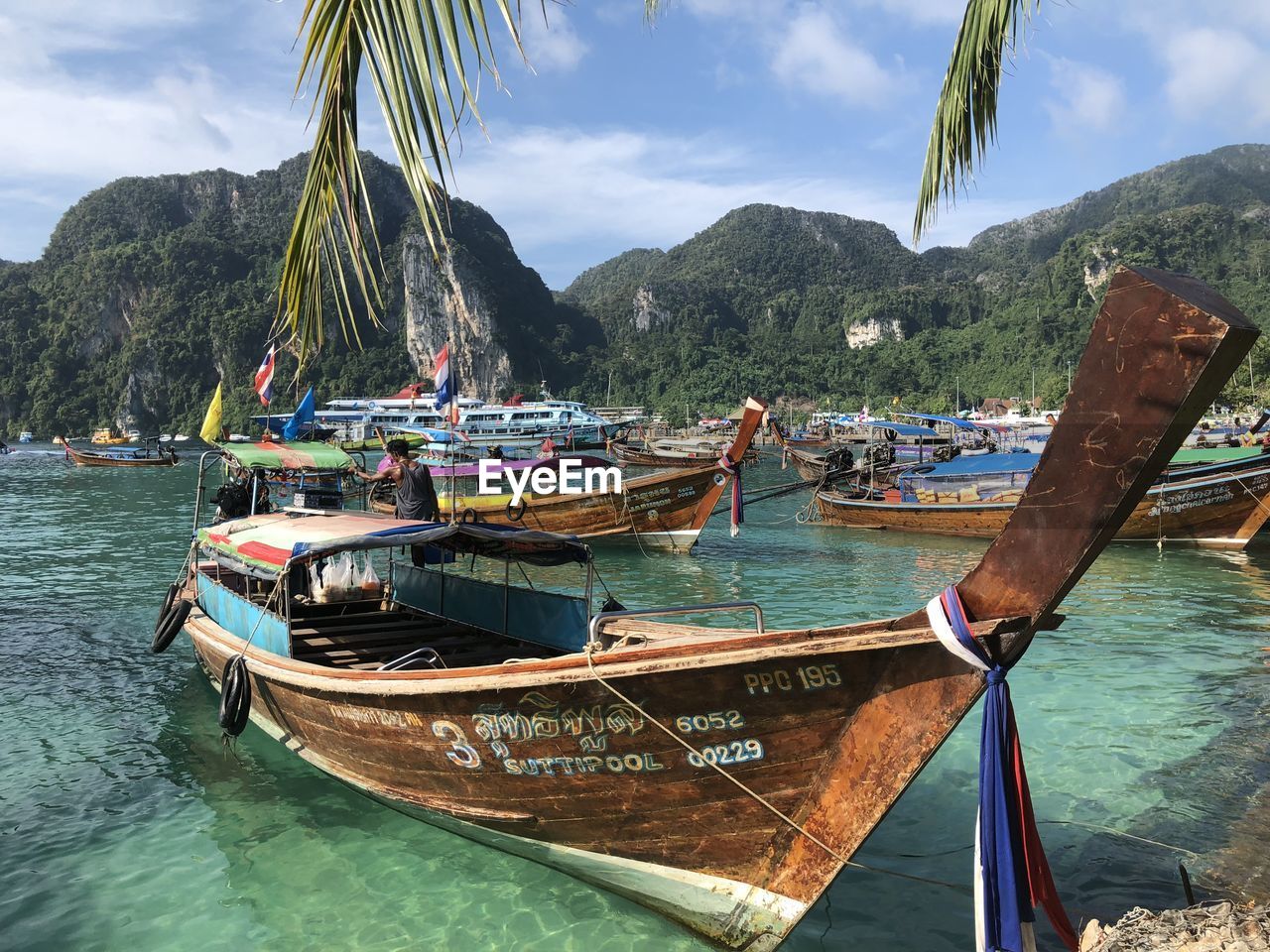 water, nautical vessel, transportation, long-tail boat, mode of transportation, sea, nature, mountain, tropical climate, land, moored, vehicle, boat, beach, travel, sky, travel destinations, scenics - nature, beauty in nature, palm tree, tree, boating, bay, day, tranquility, no people, ship, outdoors, vacation, watercraft, cloud, tourism, idyllic, island, plant, tranquil scene, trip, holiday, mountain range, coastline, bay of water, non-urban scene