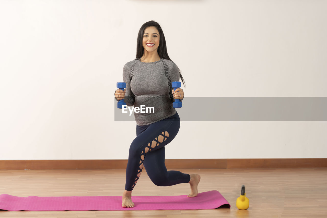 Pregnant woman exercising with dumbbells at home
