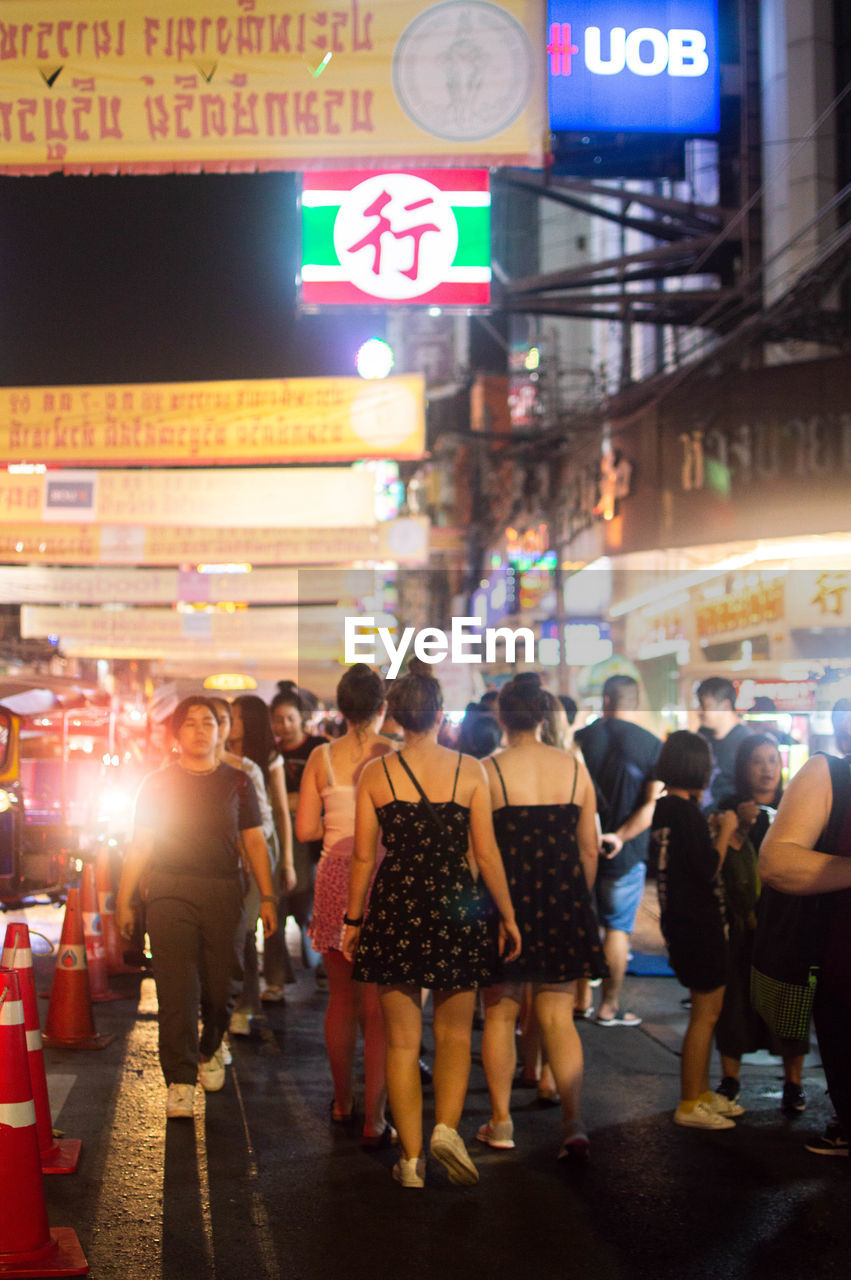 GROUP OF PEOPLE WALKING ON CITY STREET AT NIGHT