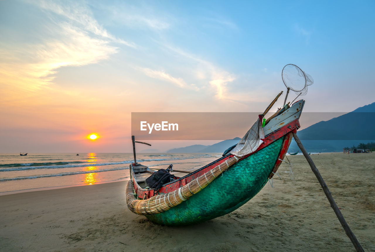 FISHING BOAT ON BEACH AGAINST SKY AT SUNSET