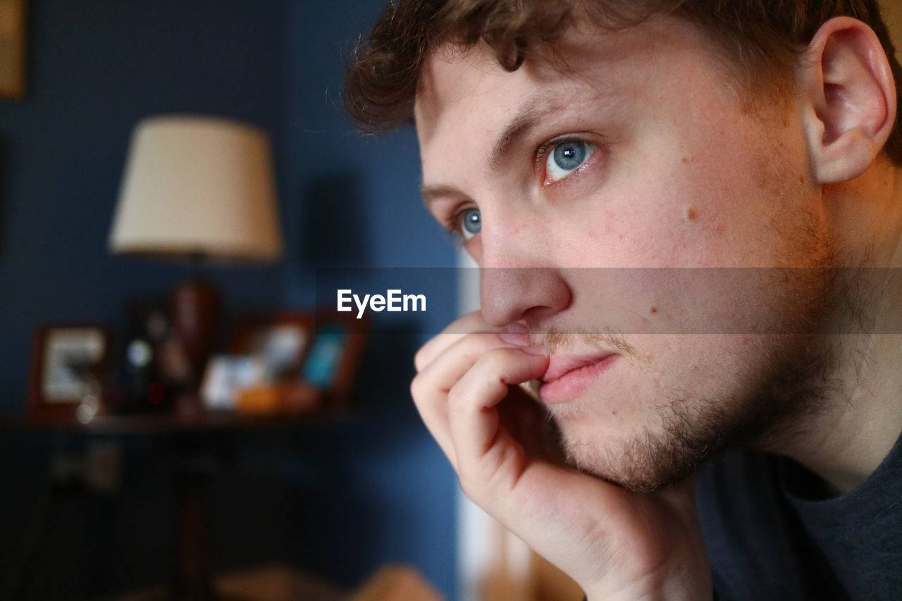 Close-up of thoughtful young man looking away at home