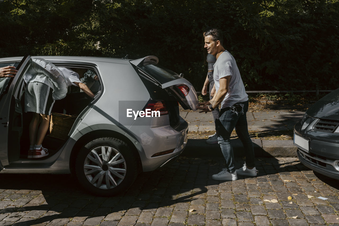 Family with electric car at roadside during sunny day