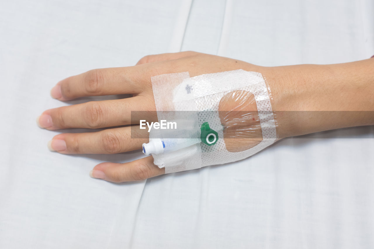 Cropped hand of woman with iv drip attached in hospital