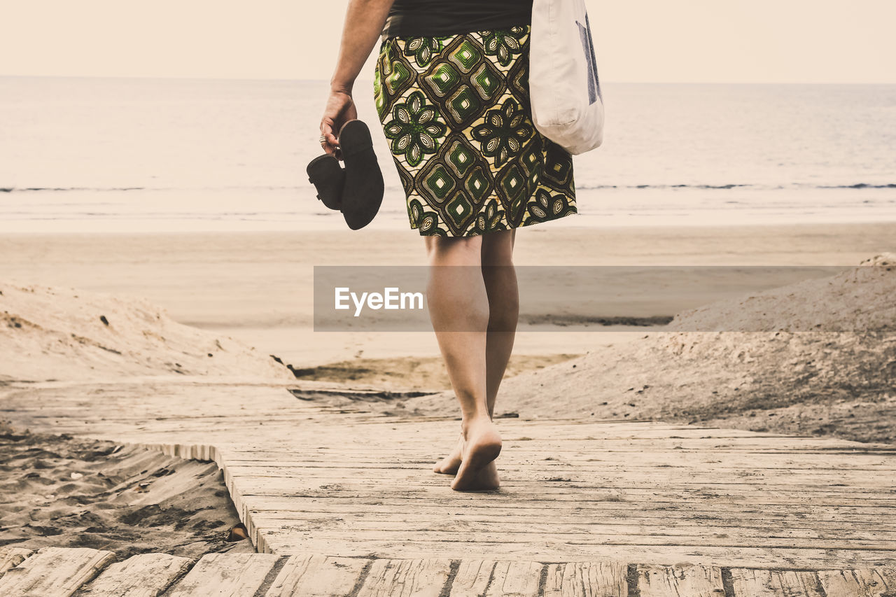 Low section of woman walking at beach