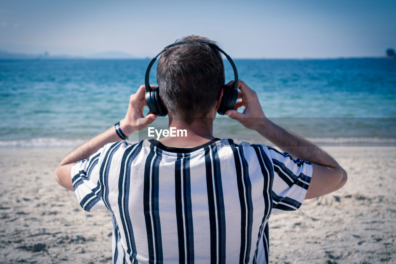 Relaxed man on the beach listening to music with his headphones