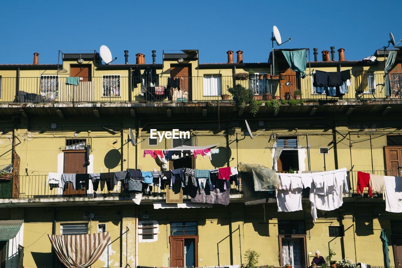LOW ANGLE VIEW OF CLOTHES DRYING AGAINST BUILDINGS