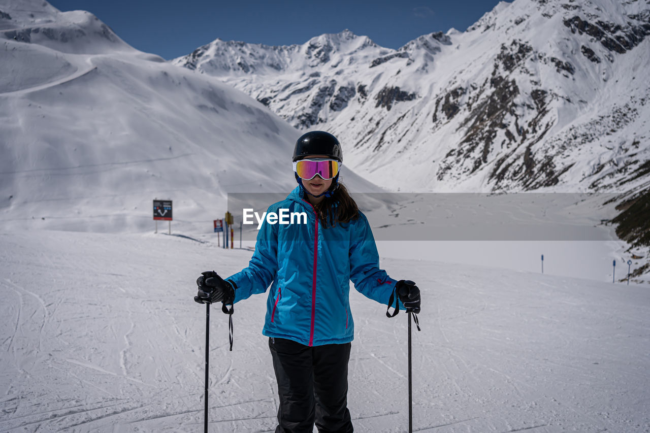 Young women with ski goggles in tirol in blue ski jacket and helmet