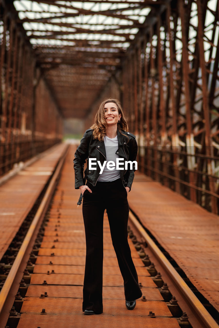 PORTRAIT OF WOMAN STANDING ON RAILROAD TRACK