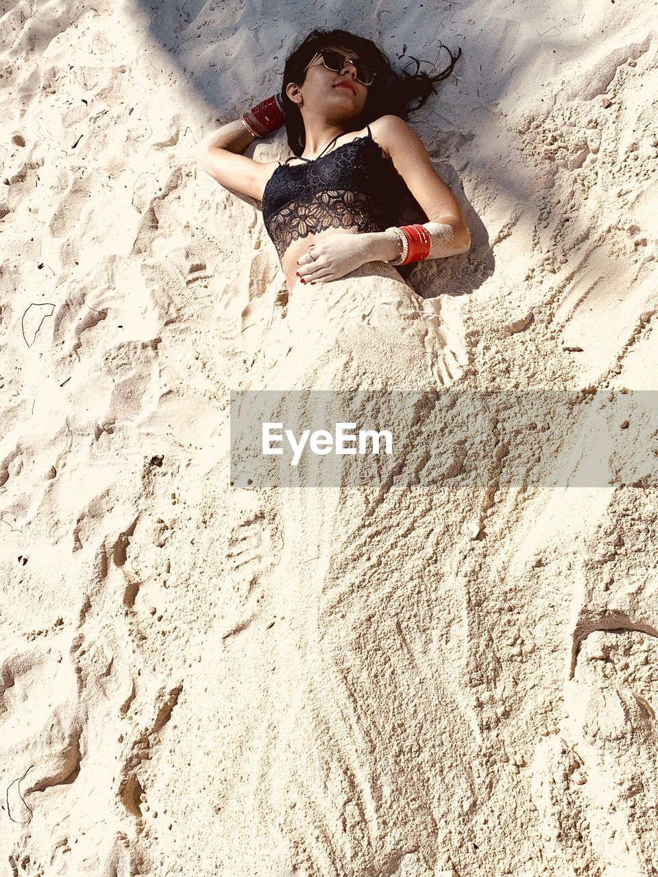 High angle view of woman buried in sand at beach