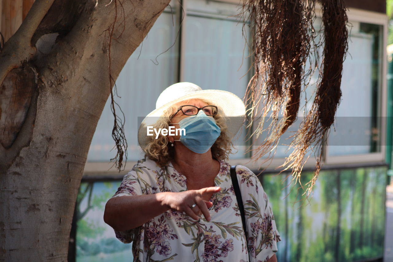 Portrait of woman standing by tree trunk