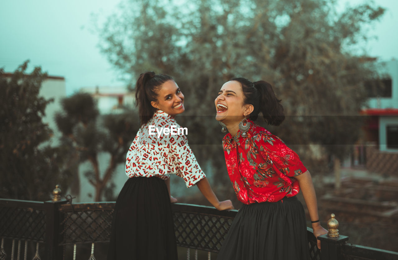 HAPPY WOMAN STANDING AGAINST PEOPLE AT THE BACKGROUND