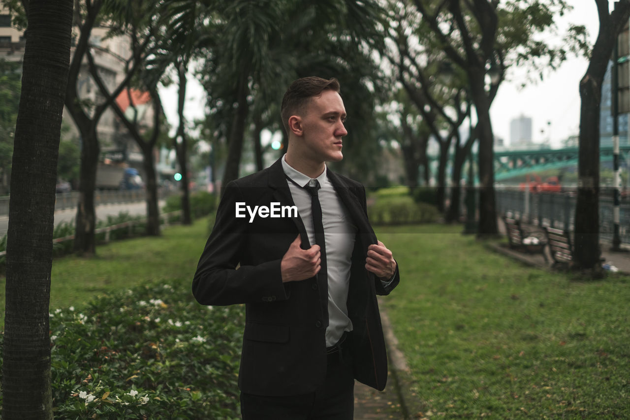 portrait of young man standing against trees