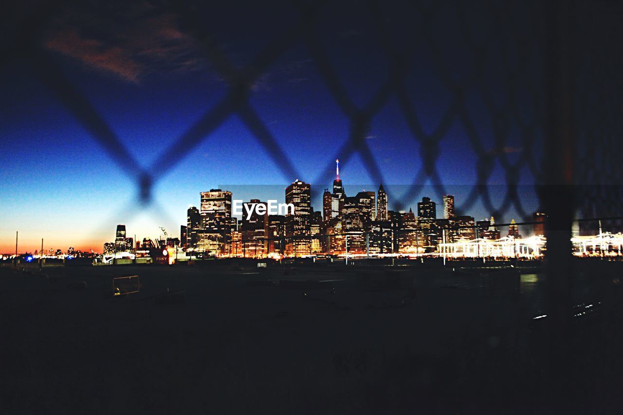 City lit up at night viewed through fence
