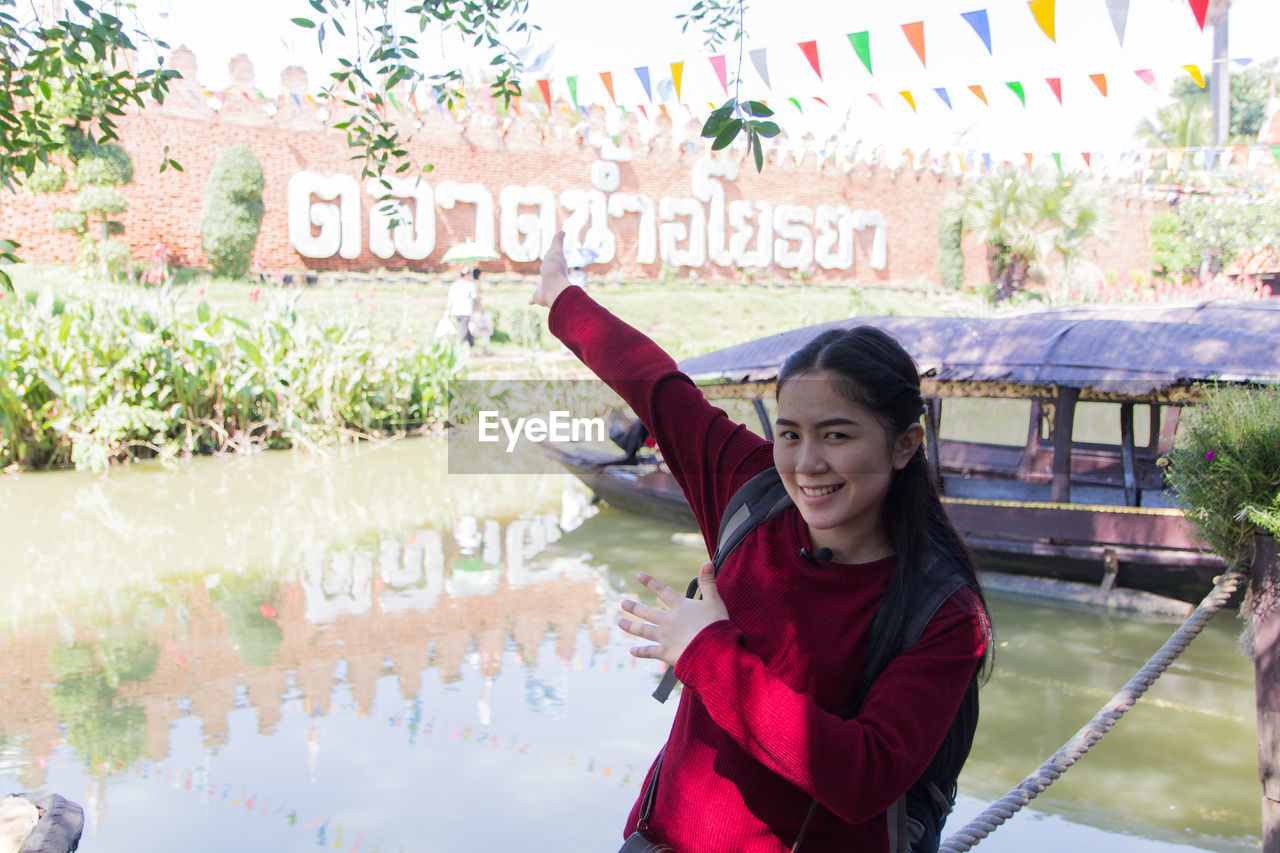 Portrait of woman pointing at text against lake