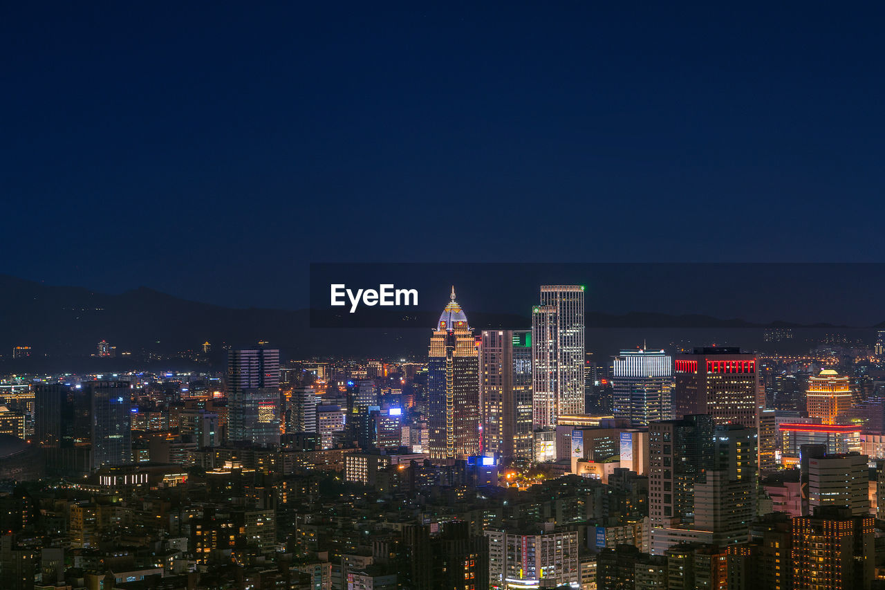 Illuminated modern buildings against clear sky at night