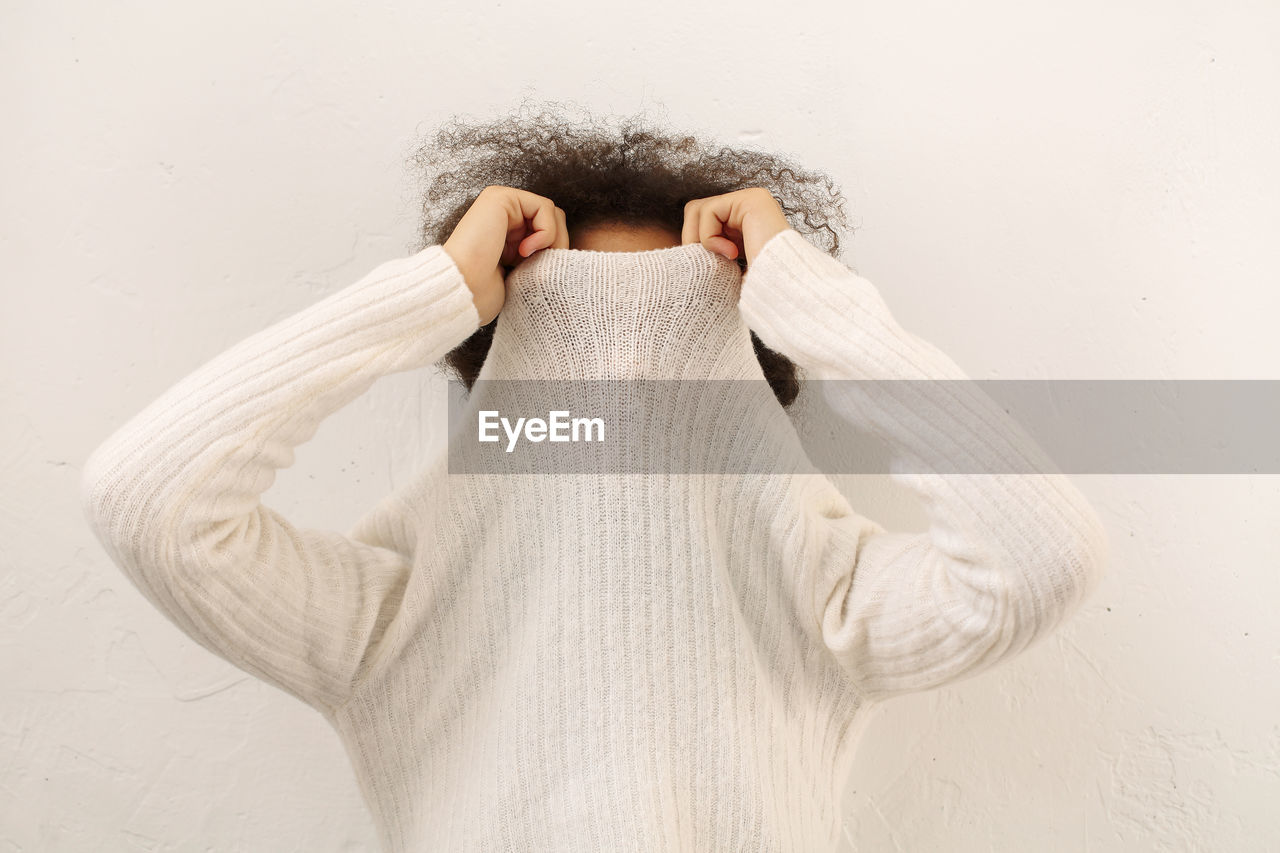 Teenager girl covering face with sweater