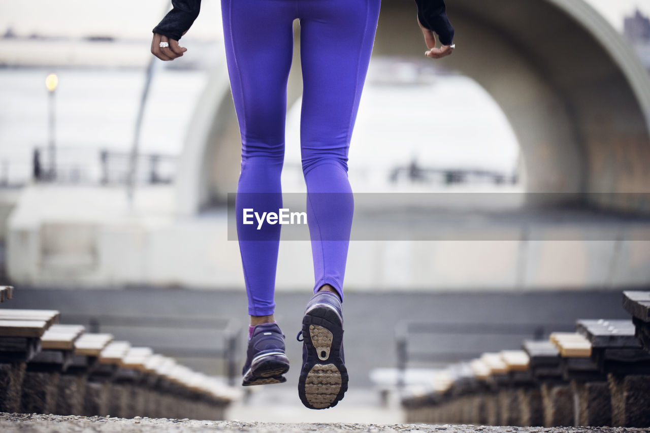 Low section of sporty woman jogging at stadium