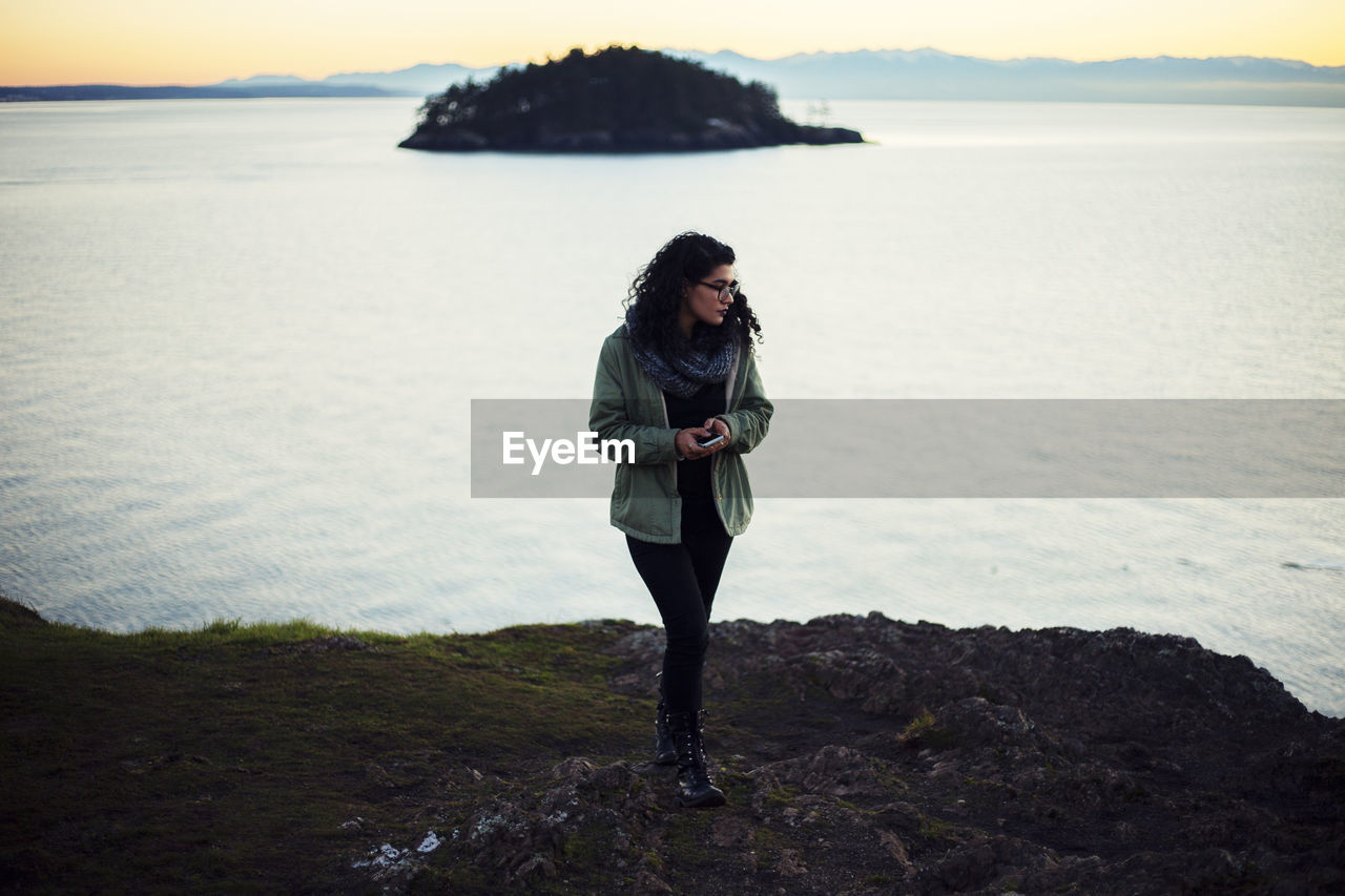 WOMAN STANDING ON ROCK AT BEACH