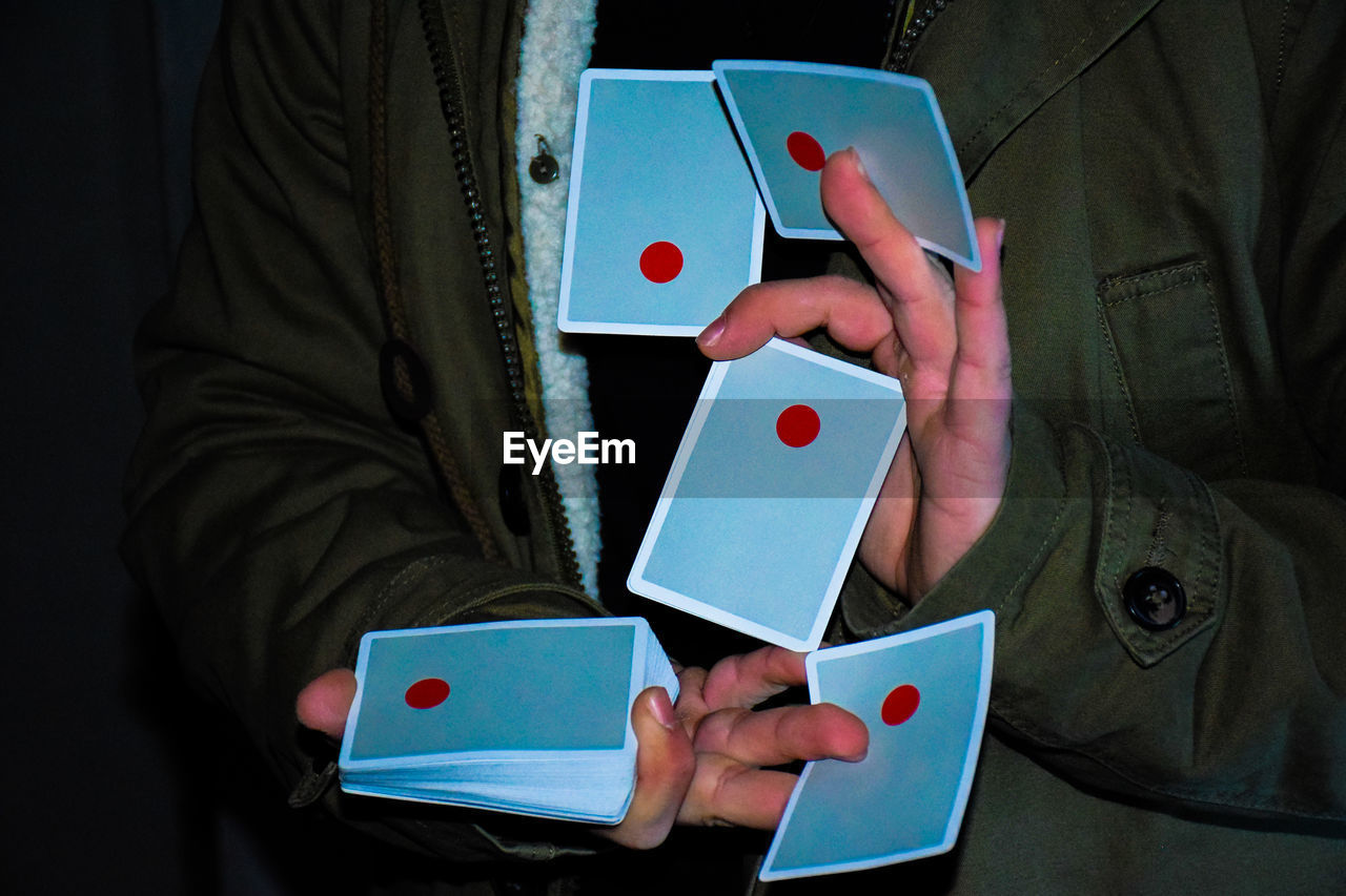 Midsection of illusionist holding cards