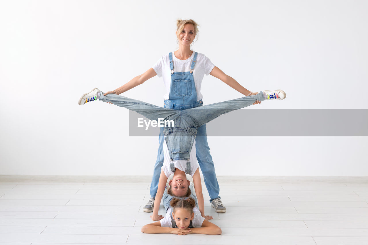 PORTRAIT OF WOMAN WITH ARMS RAISED ON FLOORING