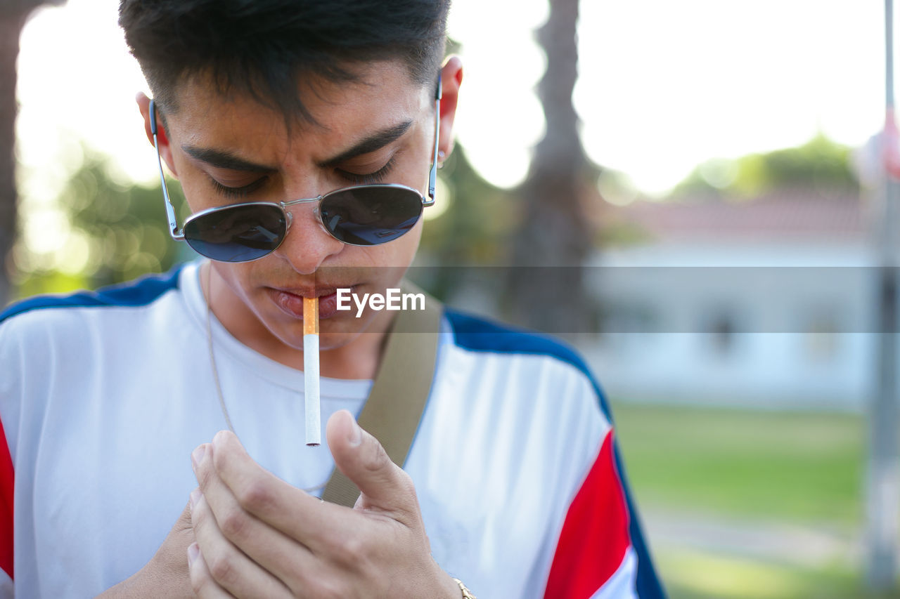 A young guy smoking a cigarette and wearing sunglasses