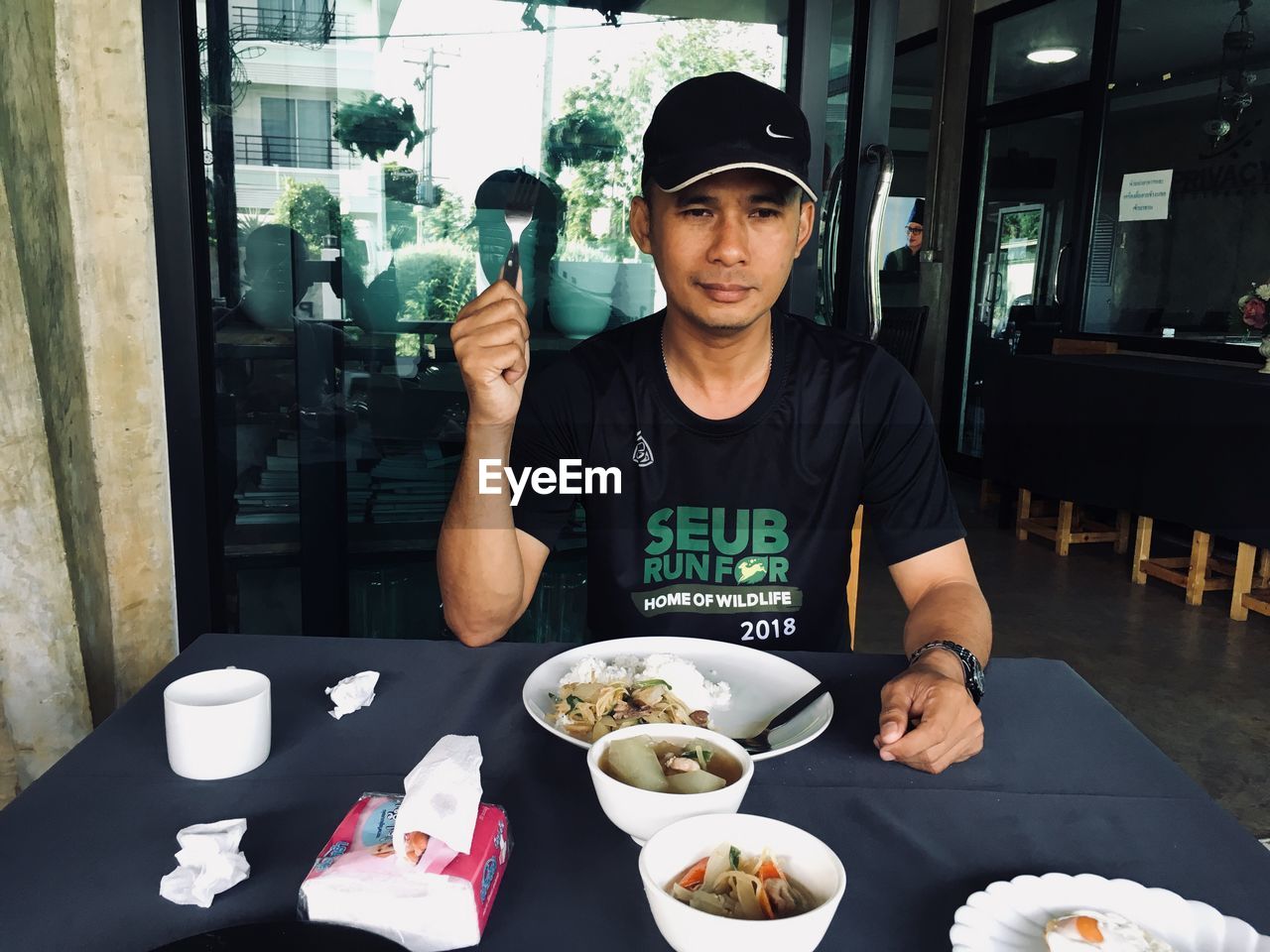 PORTRAIT OF YOUNG MAN SITTING AT RESTAURANT