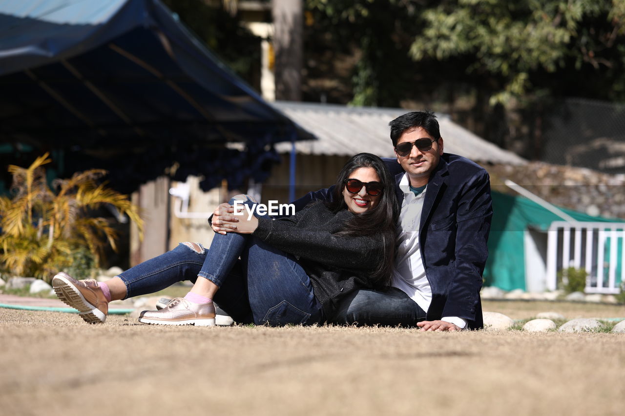 Portrait of smiling couple sitting against built structure