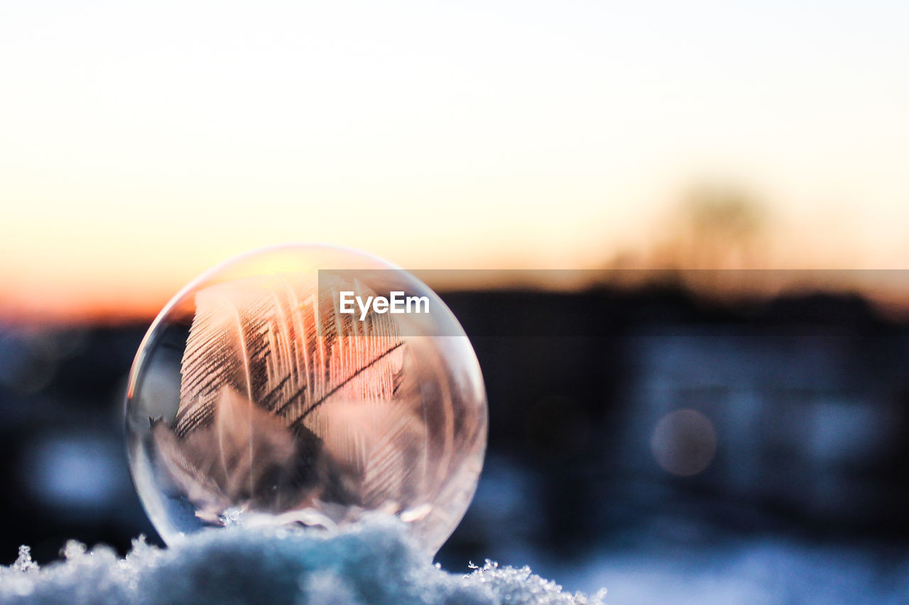 Close-up of frozen bubble against sky during sunset