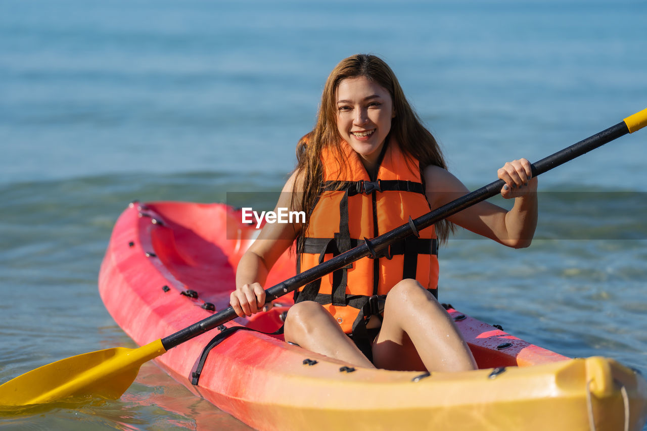 portrait of smiling young woman in boat in sea