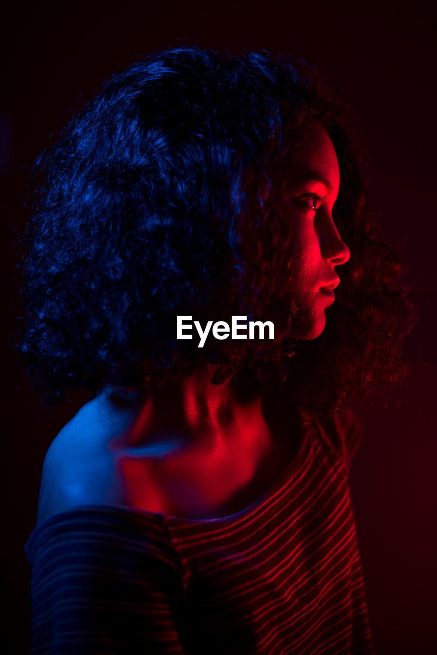 Close-up portrait of young woman against black background