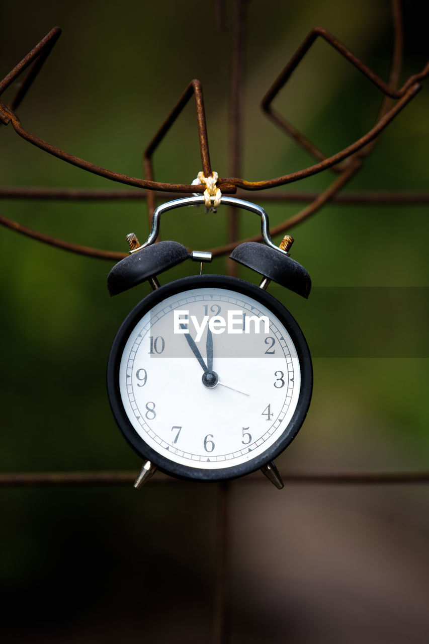 Close-up of clock hanging on rusty metal