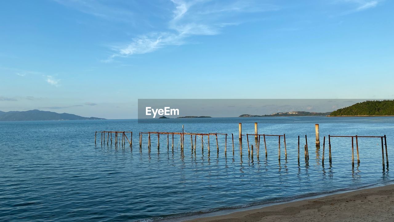 water, sky, shore, sea, body of water, ocean, scenics - nature, horizon, beauty in nature, nature, beach, tranquility, vacation, tranquil scene, land, coast, bay, blue, cloud, no people, day, pier, idyllic, outdoors, travel destinations, wood, wave, sand, non-urban scene, travel, mountain, wooden post, post, architecture, horizon over water, holiday, landscape, coastline, environment, seascape, reflection