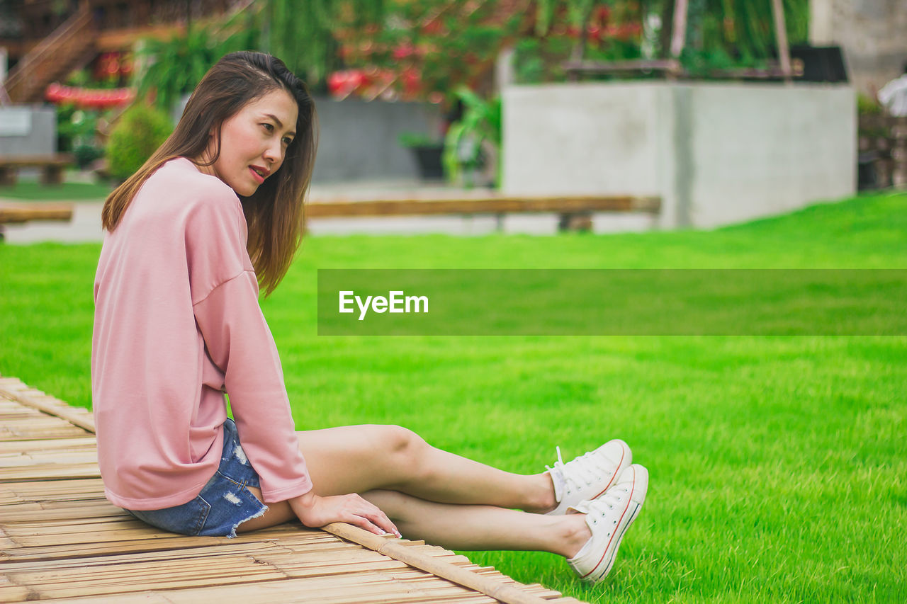 Woman looking away while sitting on field