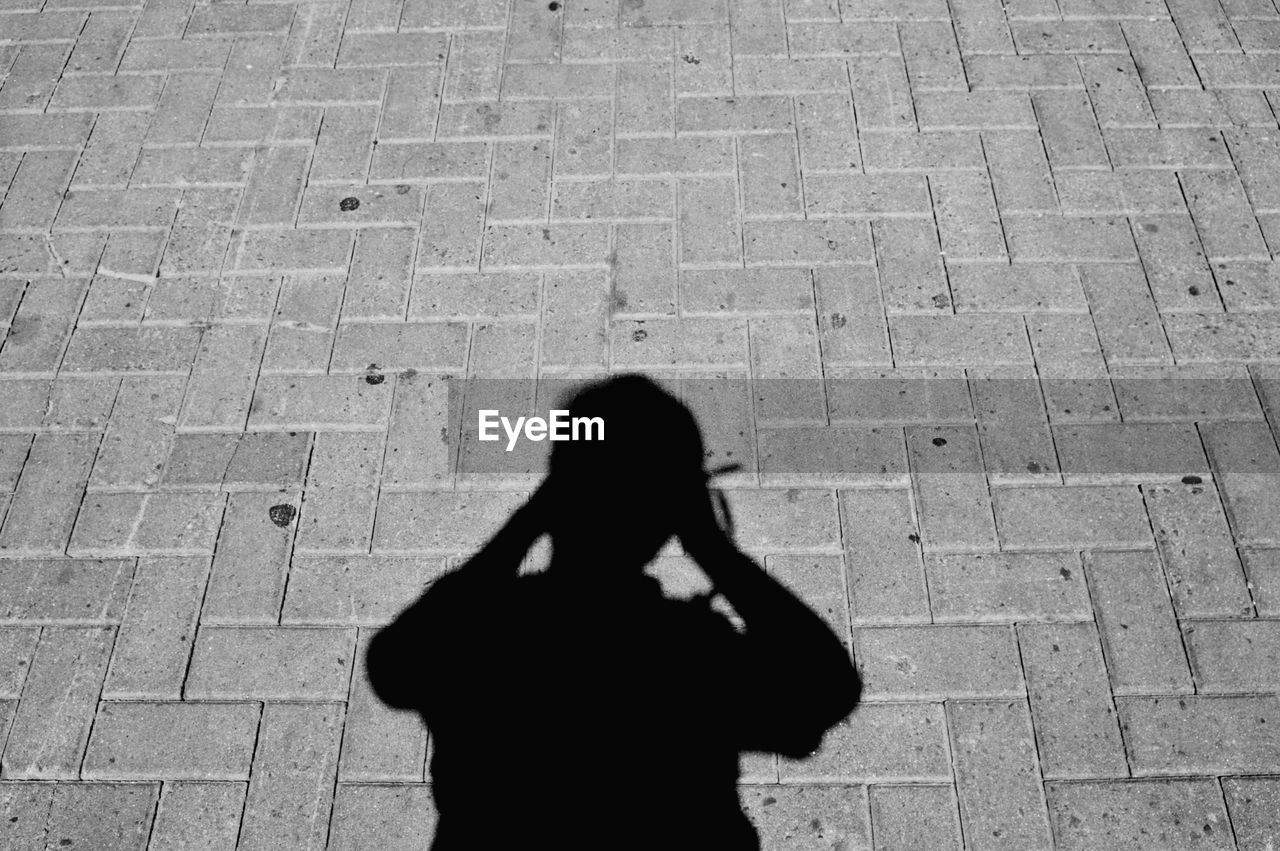 Shadow of man standing on cobblestone street