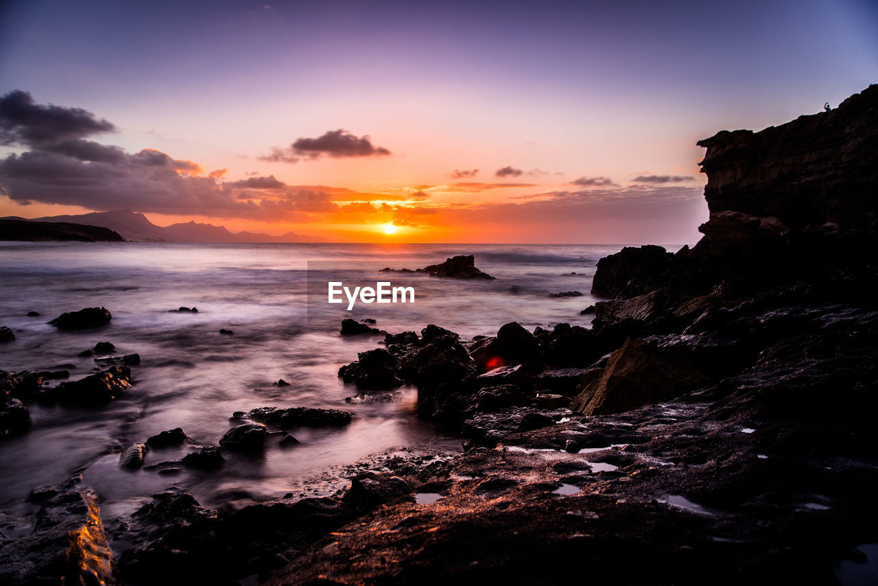 SCENIC VIEW OF SEA AGAINST ORANGE SKY