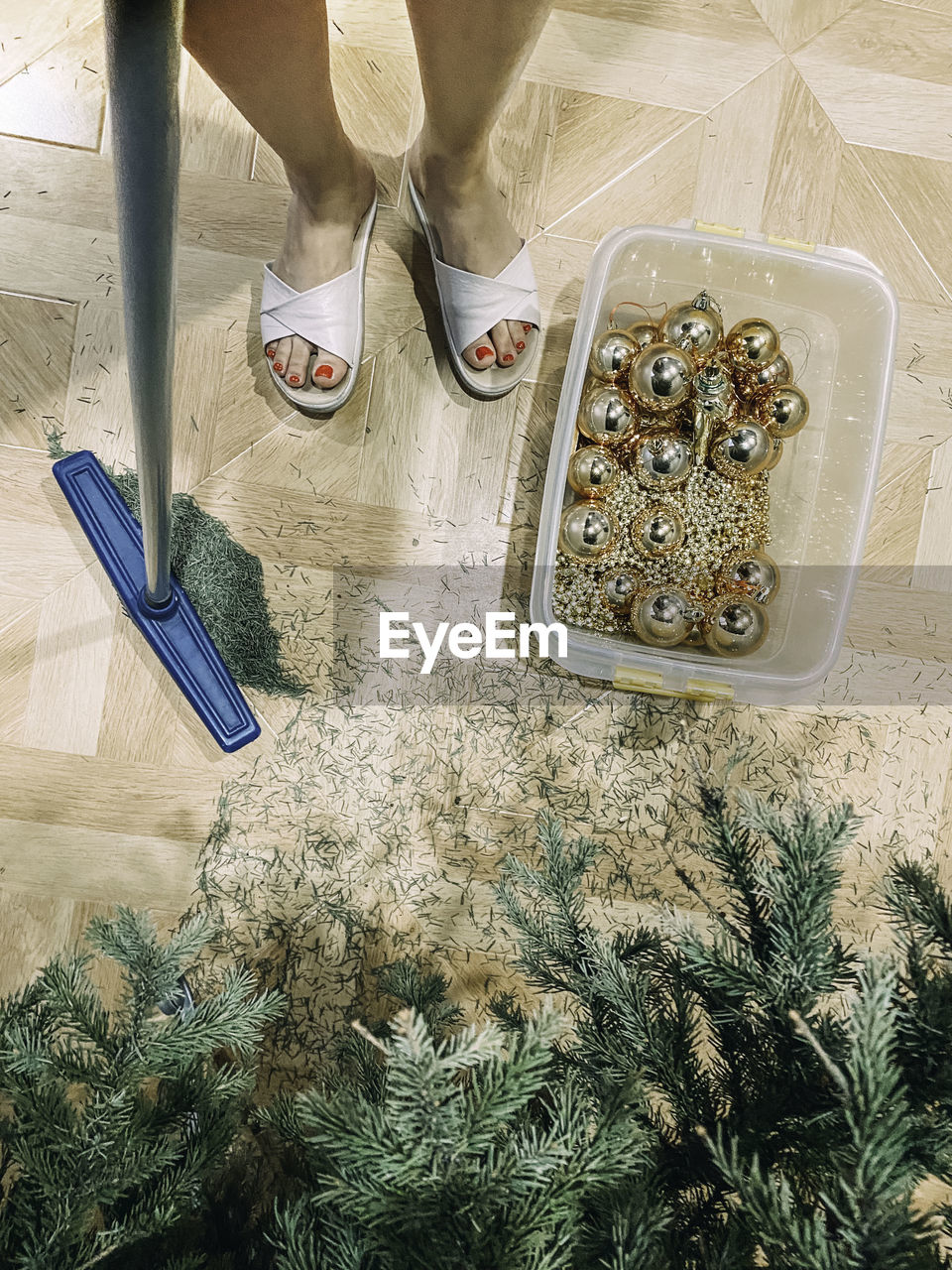 Cleaning of dry christmas tree with toy balls on the floor and needles crumbled. after new year