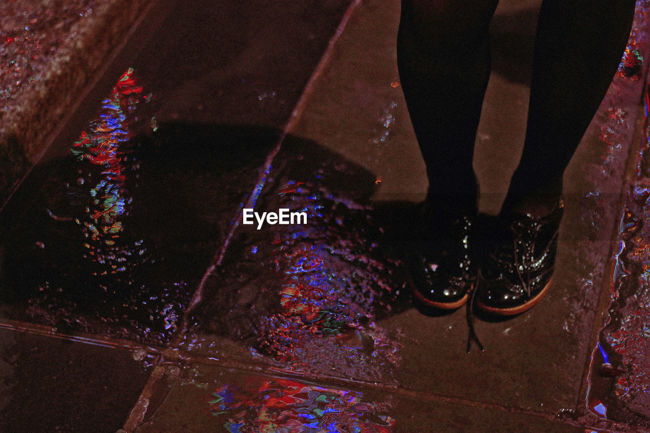 Low section of woman standing on wet floor during rainy season