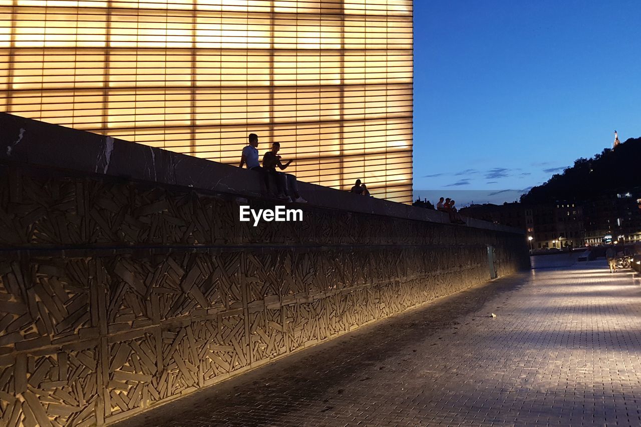 PEOPLE ON WALL AGAINST SKY