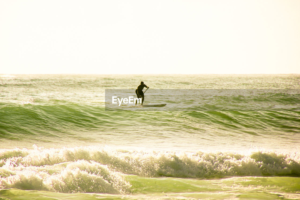 MAN ON SHORE AGAINST CLEAR SKY