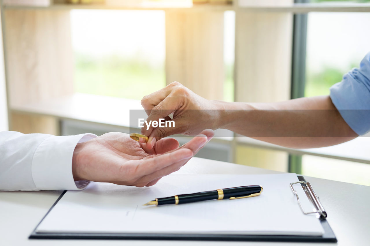 Hands of couple holding ring over clipboard