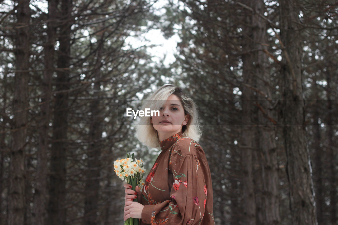 Portrait of woman standing in snow covered forest