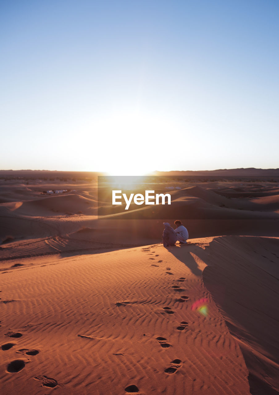 Scenic view of desert against clear sky during sunset