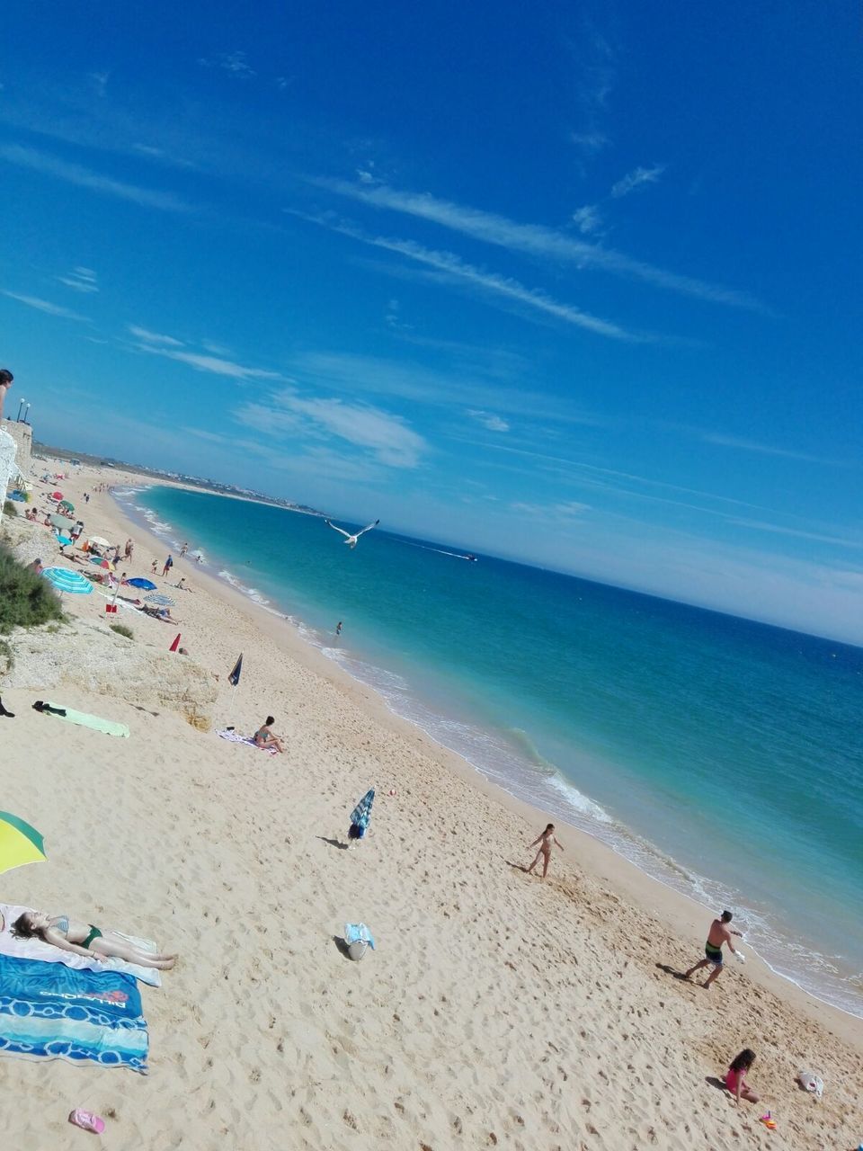 PEOPLE ENJOYING AT BEACH AGAINST BLUE SKY